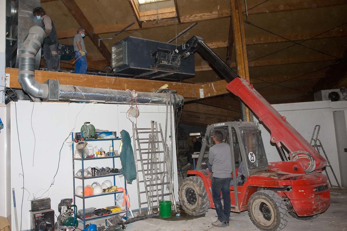 ouvriers sur un chantier déplacants une centrale de traitement de l'air à l'aide d'un chariot téléscopique